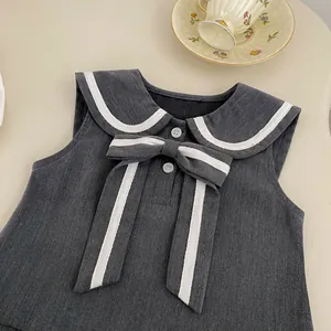Detalle de chaleco gris de estilo marinero para niña con lazo y ribetes de rayas blancas