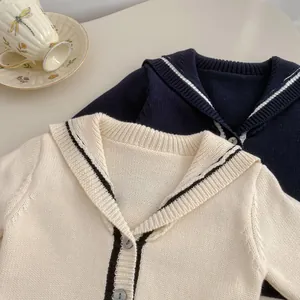 Detail of knitted cardigan with sailor collar and contrast stripes in navy and cream