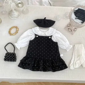 Dettaglio della camicia con colletto in pizzo e abito a pois con balze sul fondo