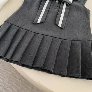 Detalle de vestido plisado gris oscuro de estilo colegial con raya blanca y botón