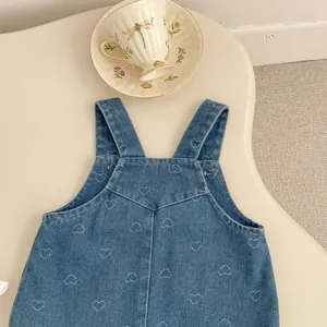 Detailed view of girls' blue denim heart dress with embroidery and V-stitch sewing