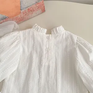Detail of white long-sleeve blouse with ruffle collar and vertical stripe texture