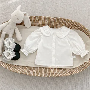Dettaglio di camicia bianca per bambina con colletto in pizzo e polsini a volant
