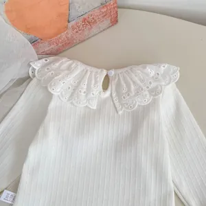 Detalle de camiseta blanca de punto acanalado con cuello de encaje bordado de niña