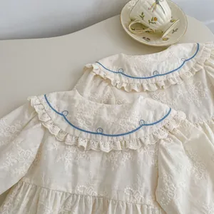Gros plan de la broderie florale sur body bébé avec détails de col festonné bleu