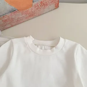 Detalle del cuello redondo acanalado en camisa de algodón blanco para niñas con costuras
