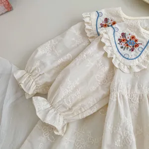 Détail de robe bébé fille avec broderie florale et col Claudine bordé de dentelle