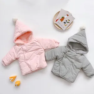 Detail of baby winter hooded coats in pink and grey with fuzzy pom-poms and warm lining