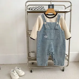 Dettaglio completo neonato con salopette in denim panda e maglia a nido d'ape