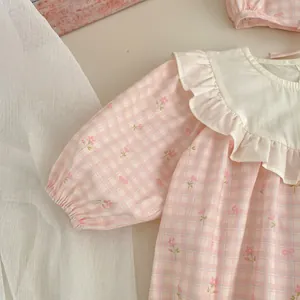Dettaglio pagliaccetto neonata a quadri floreali rosa con colletto a balze e cappello