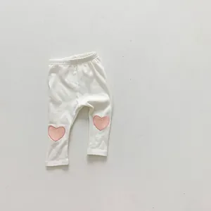 Détail de legging bébé avec patchs genoux cœurs roses sur maille blanche douce
