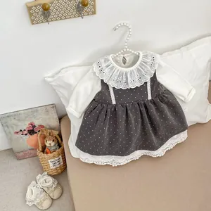 Detalle de conjunto para bebé niña con cuello de encaje y vestido gris con lunares