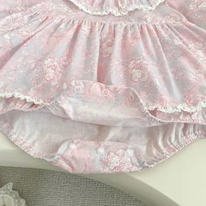 Dettaglio del body neonata a fiori con bordo in pizzo e bottoni a pressione