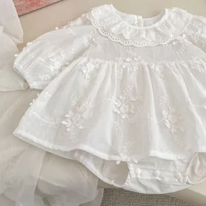 Detail of white infant bodysuit with lace collar and floral embroidery texture