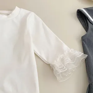 Detalle de camisa de algodón blanco con puños de encaje y textura de vestido de pichi gris