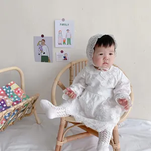 Close-up of white baby lace romper with floral embroidery and matching bonnet socks