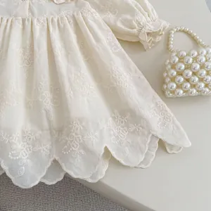 Détail de broderie florale sur robe bébé avec ourlet festonné et tissu en coton doux