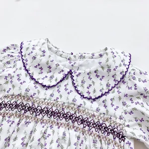 Detail of floral baby bodysuit featuring smocked chest design and embroidered Peter Pan collar