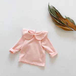 Detailopname van roze katoenen baby-T-shirt met lange mouwen en een Peter Pan-kraag