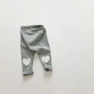 Détail de leggings gris pour bébé avec patchs coeur blancs au niveau des genoux