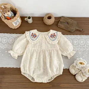 Détail d'un barboteuse bébé avec broderie florale sur col à volants et texture jacquard