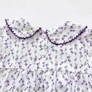 Detail of baby floral bodysuit featuring purple flower patterns and white buttons