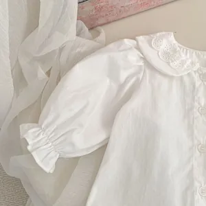 Dettaglio di camicia bianca da bambina con colletto Peter Pan e ricamo in pizzo fine