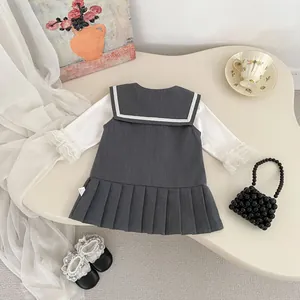 Detalle de conjunto vintage para niña con vestido plisado y camisa con puños de encaje