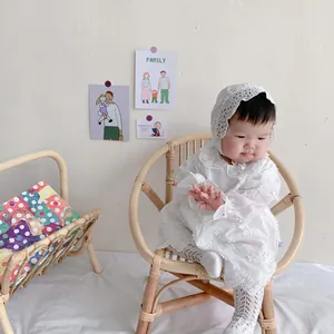 Detail of white cotton lace embroidery on baby romper dress with matching bonnet