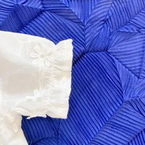 Close-up of white baby romper sleeve with floral embroidery and elastic smocked cuffs