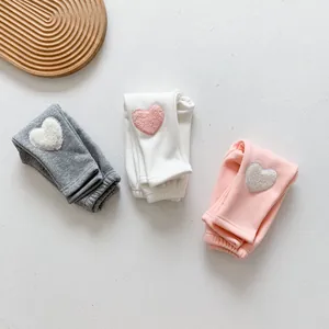Detailed close-up of baby winter leggings featuring plush heart-shaped patchwork decor