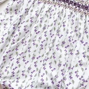Detail of baby romper featuring purple floral pattern and handmade smocking stitching