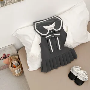 Detalle de vestido gris para niña con cuello de lazo blanco y encaje en las mangas