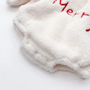 Detail of soft plush baby romper showing white resin snap buttons and Merry embroidery