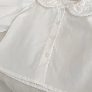 Dettaglio del colletto Peter Pan con pizzo e ricami su una camicetta in cotone bimba