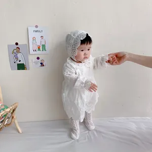 Detail of white long sleeve baby romper with floral embroidery and lace hat set