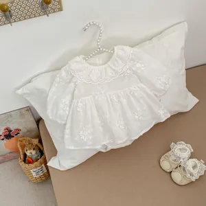 Detail of white infant bodysuit with lace collar and floral embroidery on a pearl hanger
