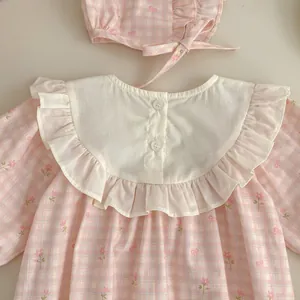 Dettaglio tutina neonata a quadretti floreali con colletto a balze e cappello