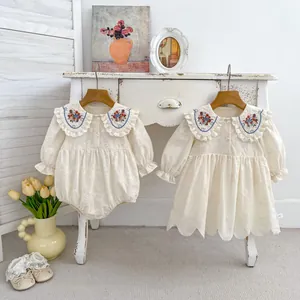Détails de robe bébé avec broderie florale sur grand col et texture ajourée