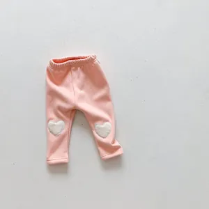 Detail of pink baby leggings with cute white plush heart patches on knees and elastic waist