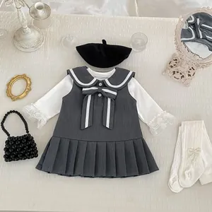 Detalle de vestido gris para niña con lazo blanco y dobladillo plisado estilo colegial
