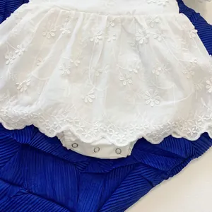 Close-up of white baby romper featuring intricate floral embroidery and scalloped hemline