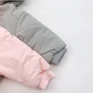 Detail of ribbed knit cuffs on padded baby jackets in light grey and pale pink colors