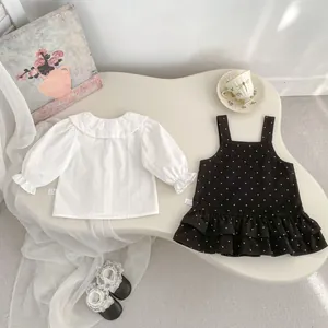 Dettaglio outfit bimba con camicia colletto in pizzo e abito a pois con volant