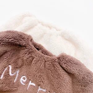 Close-up of soft brown and off-white flannel fabric with Merry embroidery detail