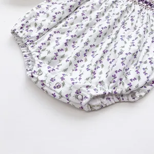 Detail of floral baby bodysuit featuring purple smocking embroidery and metal snap buttons