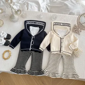 Close-up of girls' knit cardigan with 'GOOD LUCK' hood and striped flared trousers