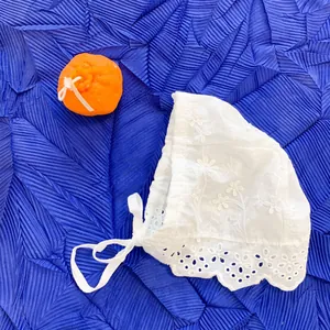 Detail view of baby white lace embroidery bonnet with floral hollow patterns