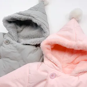 Detail of hooded baby jackets with thick plush lining and decorative white pom-poms