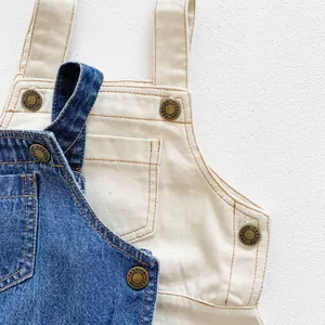 Detail of denim baby romper showing metal buttons with fashion engraving and contrast stitching